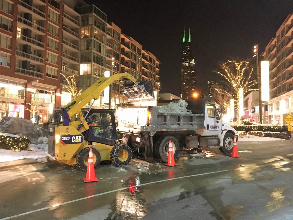 A truck being loaded in the city with snow.